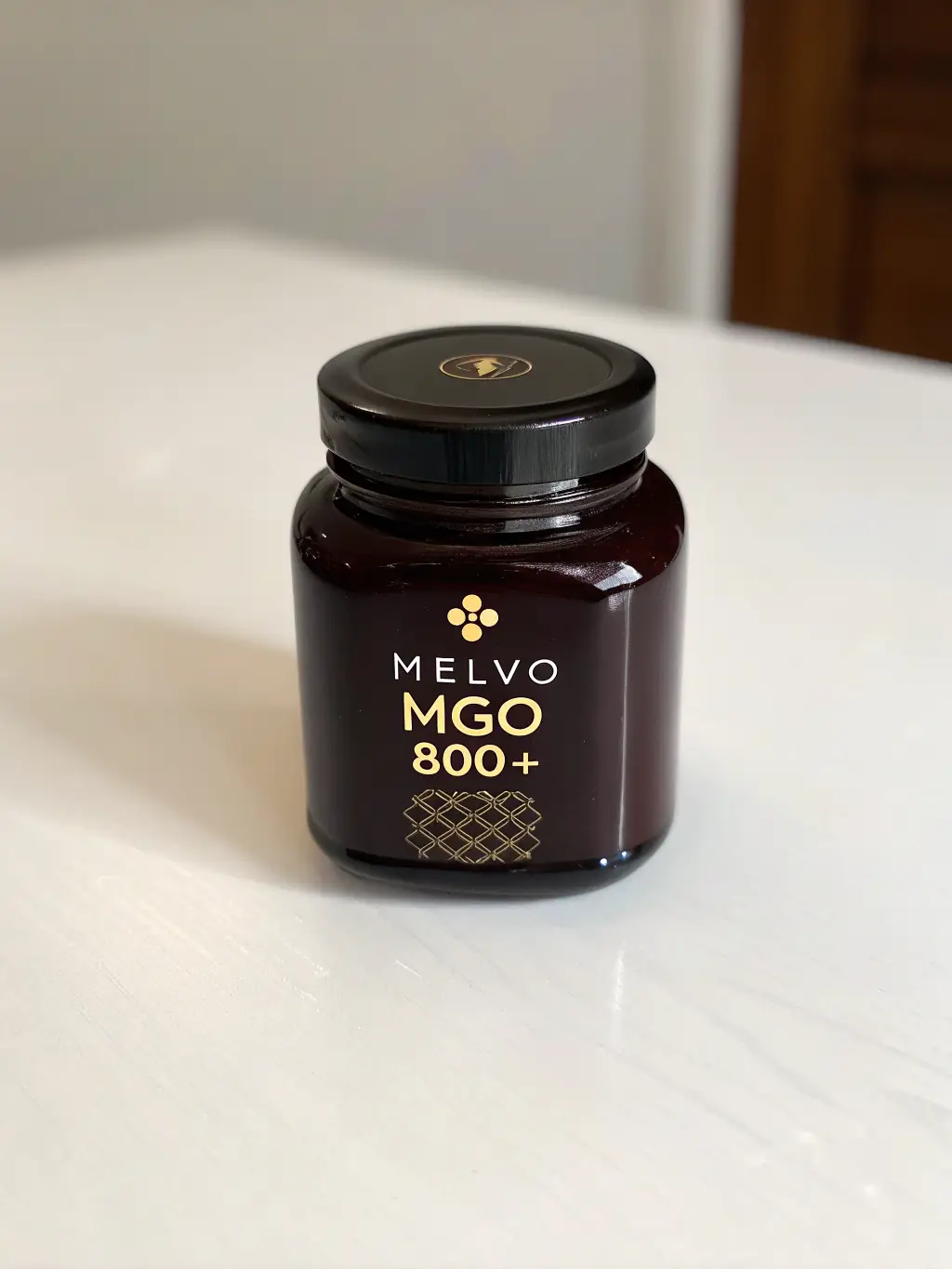 A jar of dark, almost black, Manuka honey with a label highlighting its UMF rating, placed on a clean white surface to emphasize its purity.